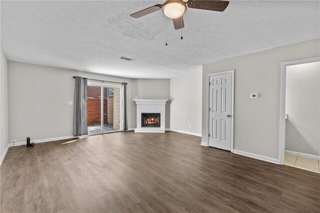 unfurnished living room featuring a ceiling fan, visible vents, wood finished floors, baseboards, and a fireplace