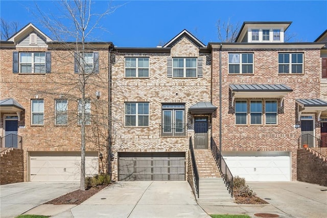 townhome / multi-family property with stairs, an attached garage, brick siding, and driveway