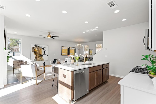 kitchen featuring sink, stainless steel appliances, light hardwood / wood-style flooring, an island with sink, and ceiling fan with notable chandelier