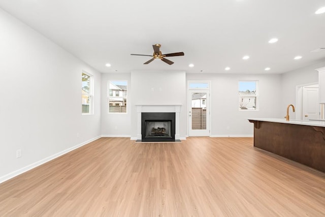 unfurnished living room with ceiling fan and light hardwood / wood-style floors