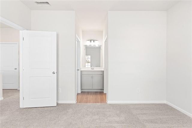 unfurnished bedroom featuring connected bathroom, light colored carpet, and sink