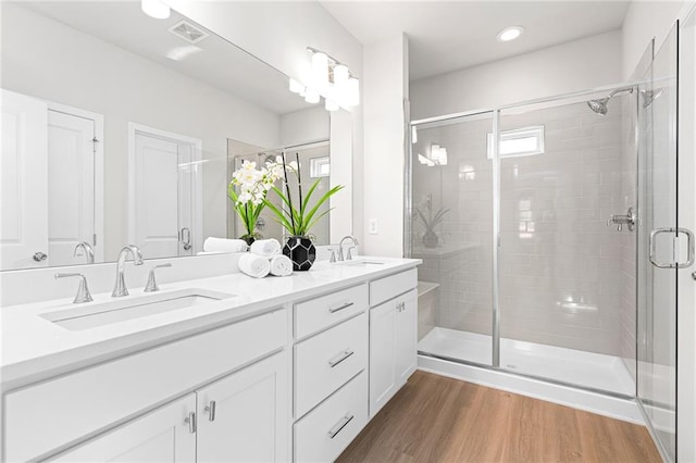 bathroom with wood-type flooring, vanity, and an enclosed shower