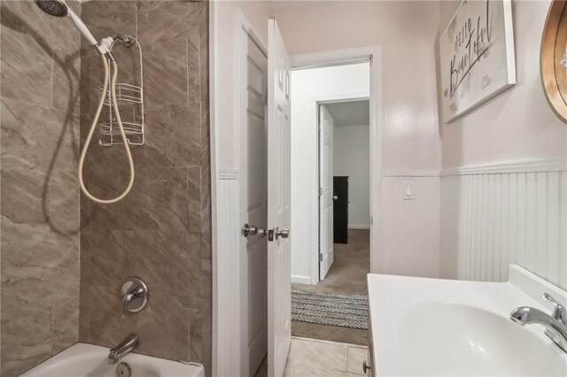 bathroom featuring tile patterned flooring, tiled shower / bath combo, and sink