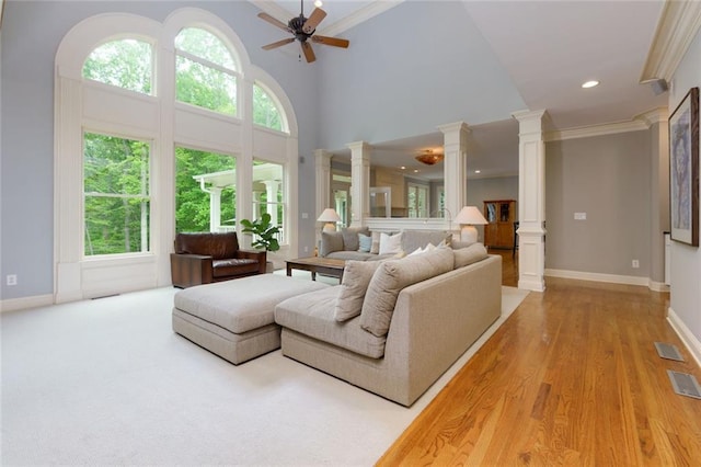 living room featuring crown molding, decorative columns, a wealth of natural light, and visible vents