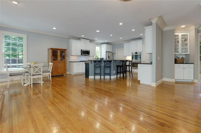 kitchen featuring crown molding, appliances with stainless steel finishes, white cabinets, and a kitchen bar