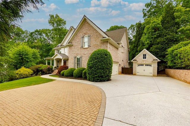 view of front of house with brick siding, driveway, an outdoor structure, and a garage