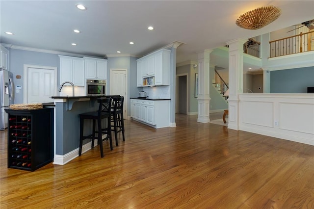 kitchen with stainless steel appliances, dark countertops, decorative columns, and ornamental molding