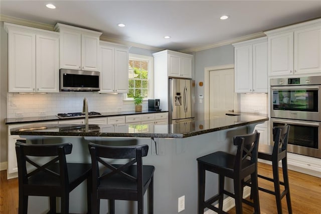 kitchen featuring crown molding, stainless steel appliances, recessed lighting, and white cabinetry