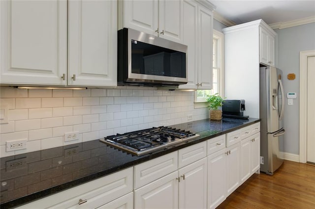 kitchen with backsplash, appliances with stainless steel finishes, baseboards, white cabinets, and ornamental molding