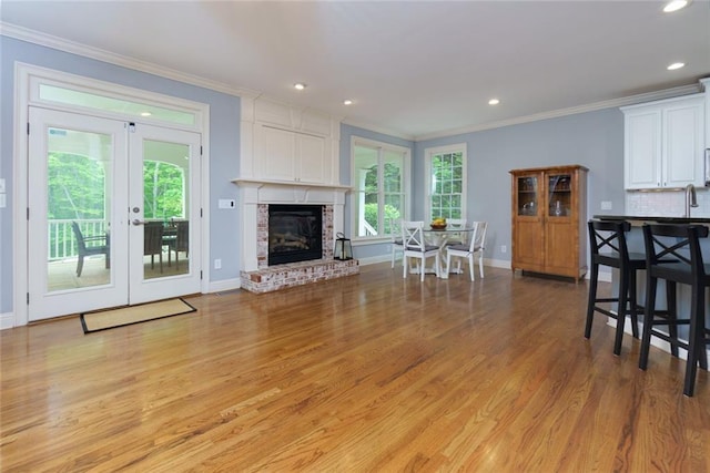 living area featuring crown molding, baseboards, french doors, and light wood finished floors