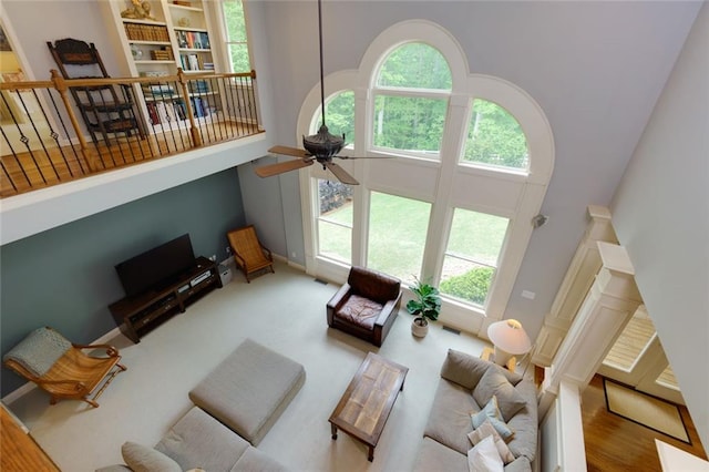 living room with a high ceiling, ceiling fan, and visible vents