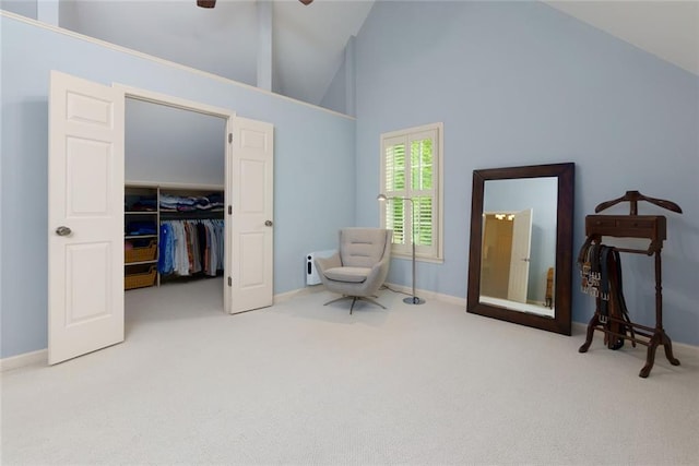 living area with carpet flooring, ceiling fan, baseboards, and high vaulted ceiling