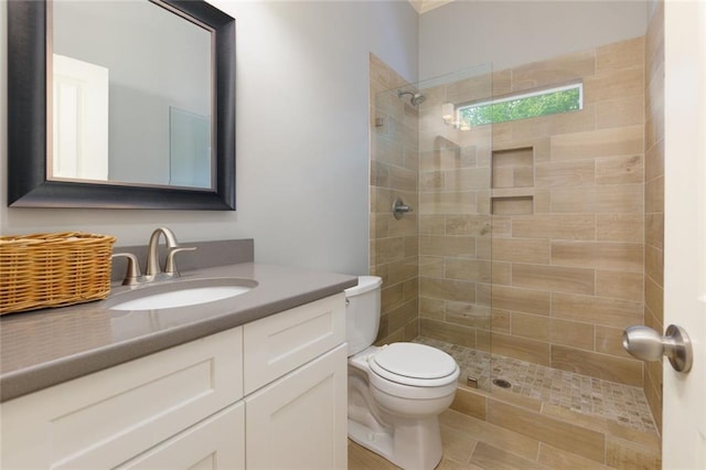 full bath featuring vanity, toilet, and tiled shower