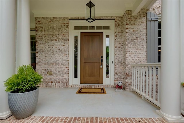 entrance to property featuring a porch and brick siding
