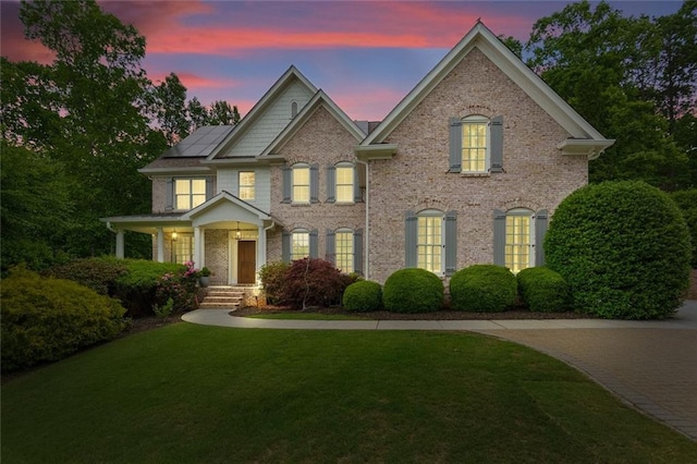 view of front of property featuring solar panels, a front lawn, and brick siding