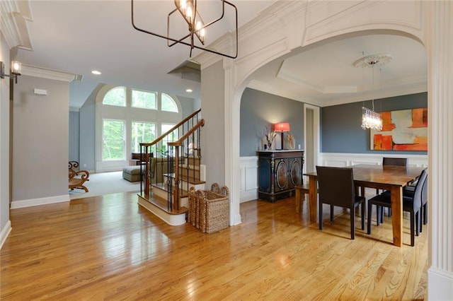 interior space featuring ornamental molding, stairway, arched walkways, light wood-style flooring, and a notable chandelier