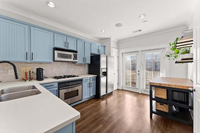 kitchen with ornamental molding, stainless steel appliances, blue cabinetry, and a sink