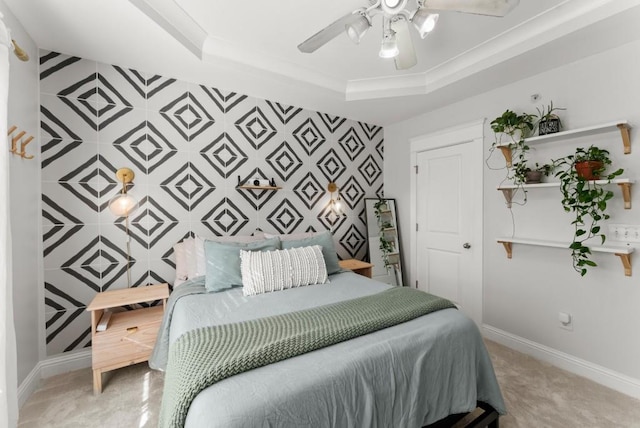 bedroom with an accent wall, a tray ceiling, ceiling fan, and baseboards