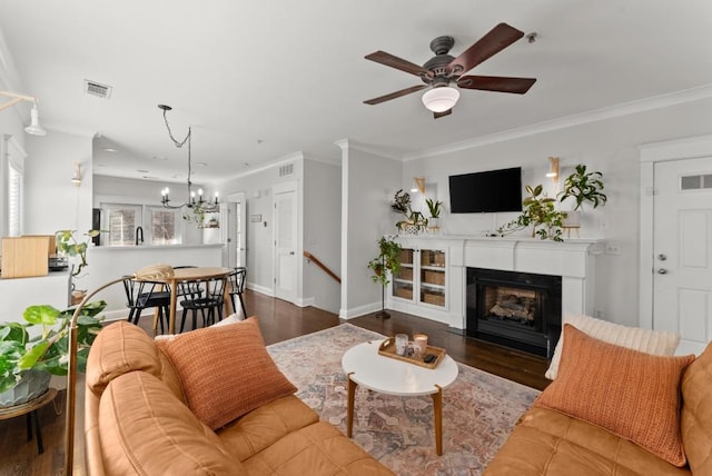 living room with a fireplace, wood finished floors, visible vents, and crown molding