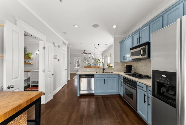 kitchen with stainless steel appliances, crown molding, light countertops, blue cabinetry, and a sink