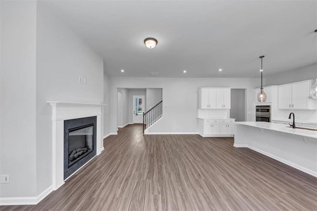 212 Birchwood Row, Canton, GA 30115 - unfurnished living room with baseboards, wood finished floors, a fireplace, stairway, and recessed lighting
