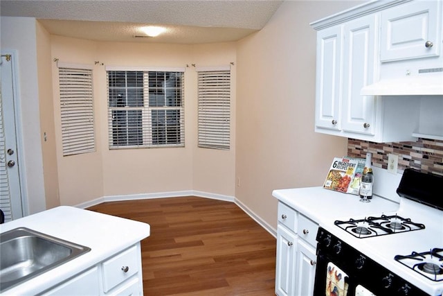 kitchen with a textured ceiling, gas range gas stove, white cabinetry, backsplash, and hardwood / wood-style floors