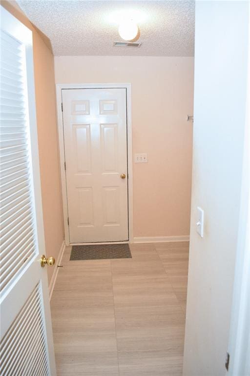 doorway to outside featuring a textured ceiling and light hardwood / wood-style flooring