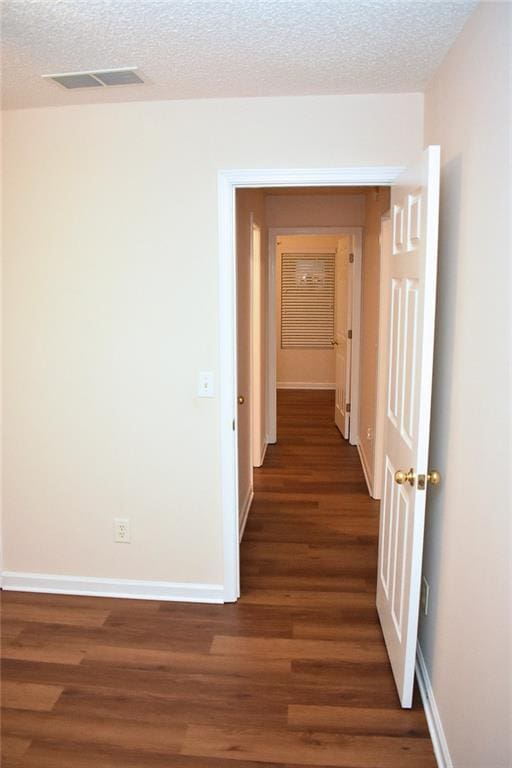 hallway featuring a textured ceiling and dark hardwood / wood-style flooring