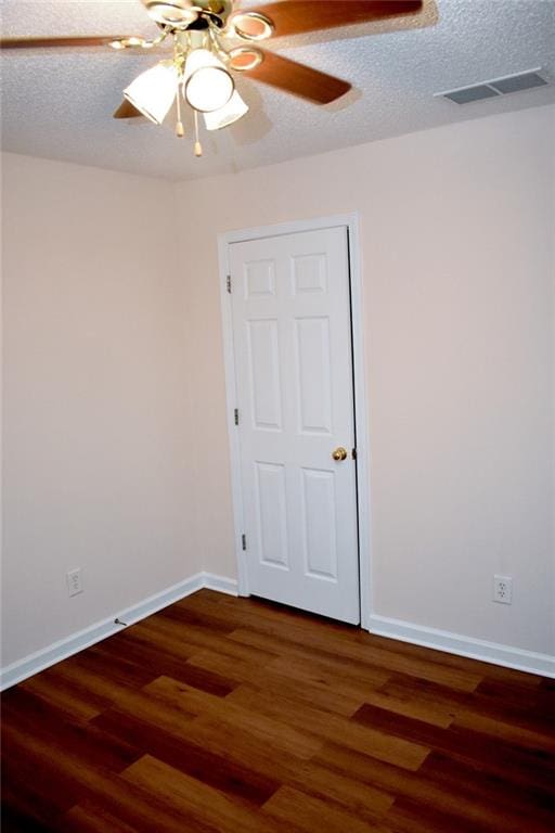 empty room with a textured ceiling, dark hardwood / wood-style floors, and ceiling fan