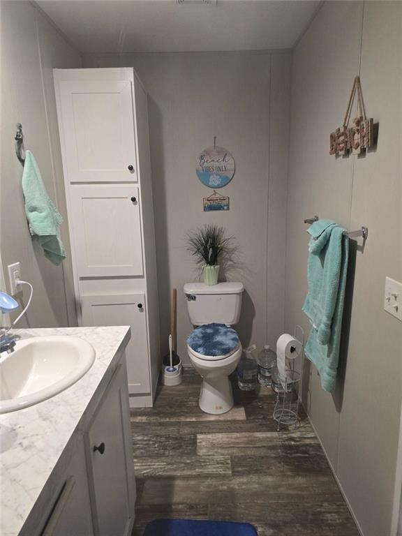 bathroom featuring toilet, wood finished floors, and vanity