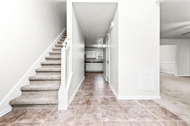 staircase featuring tile patterned floors and a textured ceiling