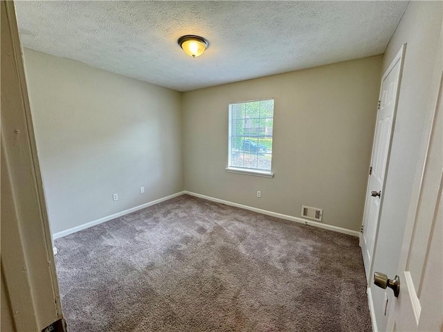 carpeted spare room with baseboards, visible vents, and a textured ceiling