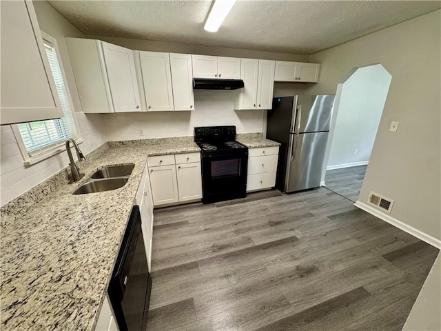 kitchen featuring a sink, visible vents, under cabinet range hood, black appliances, and wood finished floors