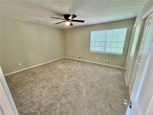 carpeted empty room featuring a textured ceiling, visible vents, ceiling fan, and baseboards
