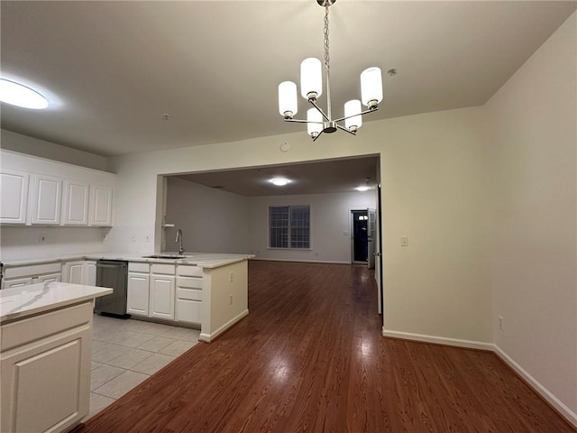 kitchen with a sink, open floor plan, white cabinetry, light wood-style floors, and a peninsula