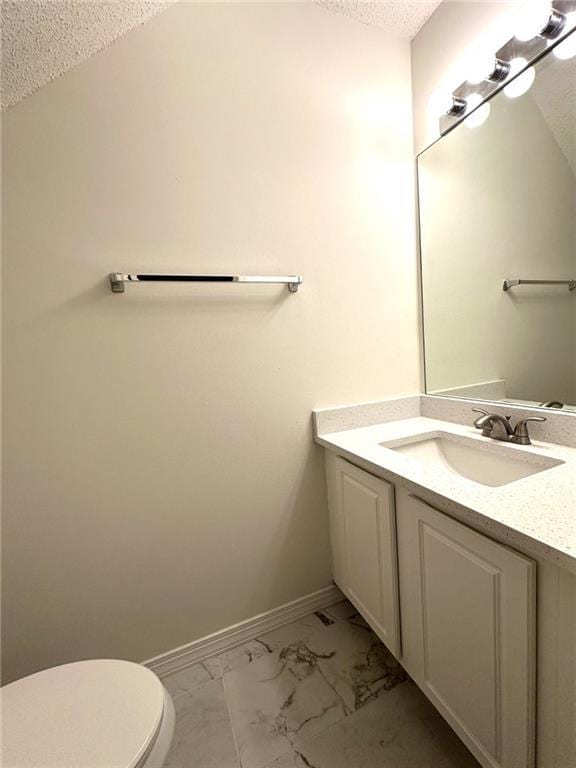 bathroom with vanity, baseboards, a textured ceiling, toilet, and marble finish floor