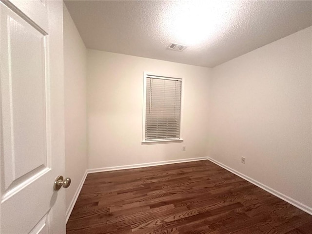 unfurnished room featuring visible vents, a textured ceiling, baseboards, and dark wood-style flooring