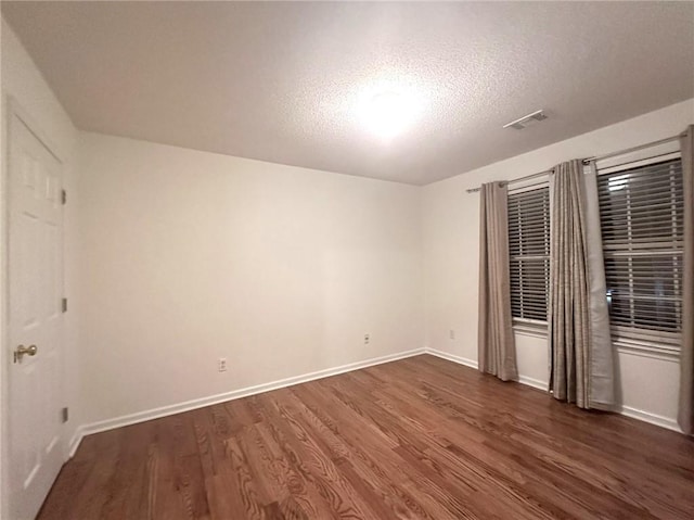 unfurnished bedroom with visible vents, dark wood-style floors, baseboards, and a textured ceiling