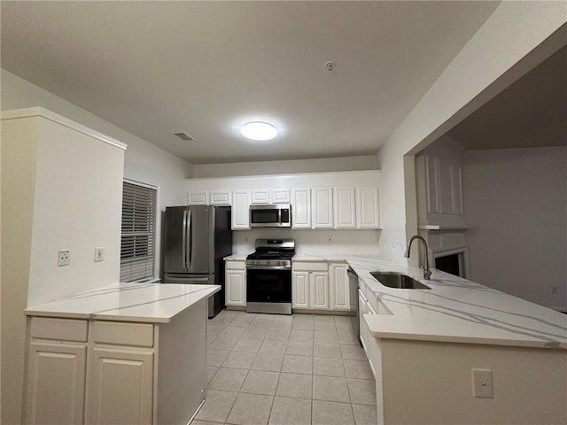 kitchen featuring a peninsula, stainless steel appliances, light countertops, and a sink