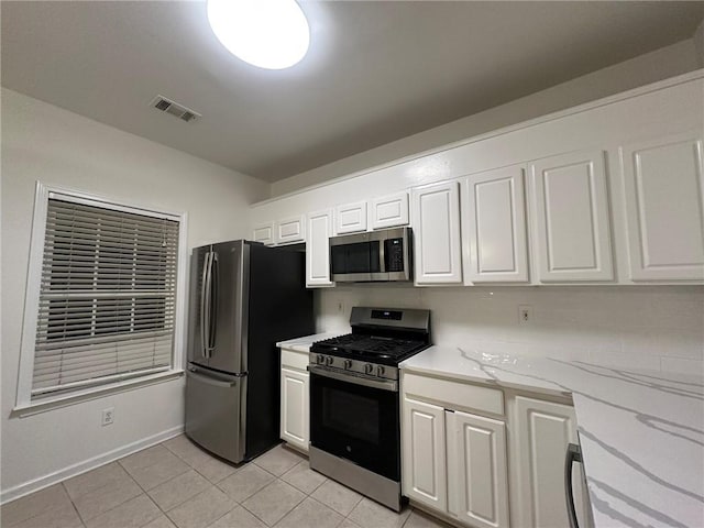 kitchen featuring visible vents, light stone countertops, light tile patterned floors, appliances with stainless steel finishes, and white cabinets