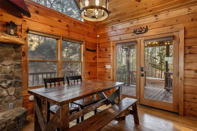 dining space featuring a notable chandelier, wooden walls, and hardwood / wood-style floors