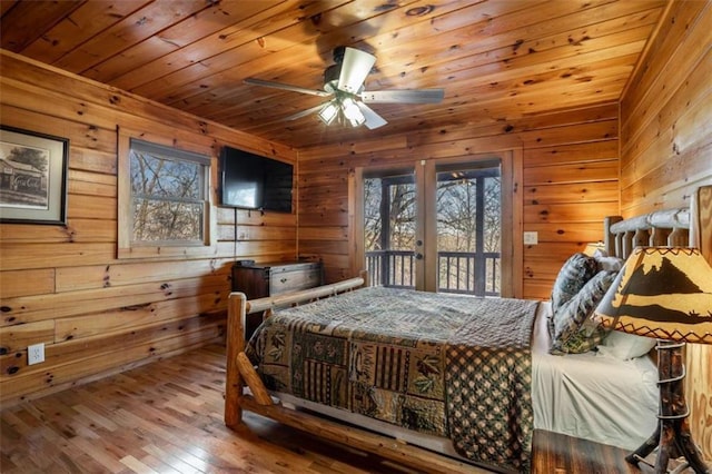 bedroom featuring french doors, multiple windows, access to outside, and hardwood / wood-style flooring