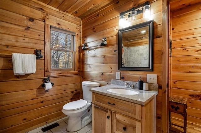 bathroom featuring tile patterned flooring, visible vents, wood walls, toilet, and vanity