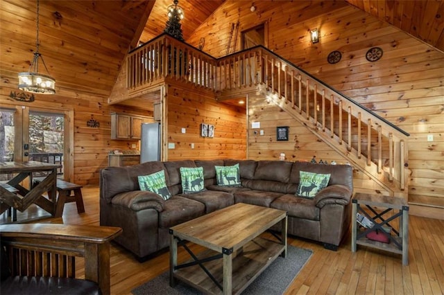 living area featuring stairway, high vaulted ceiling, wood ceiling, wood walls, and light wood-type flooring