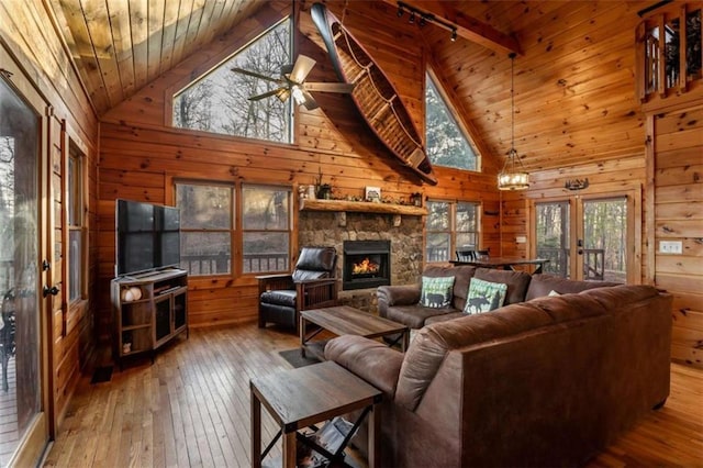 living area featuring wood-type flooring, wooden walls, wood ceiling, and a fireplace