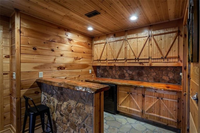 bar with recessed lighting, stone finish flooring, wooden ceiling, and wood walls