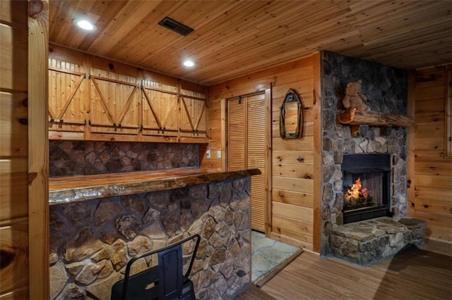 bar with wood finished floors, visible vents, a fireplace, wood ceiling, and wood walls