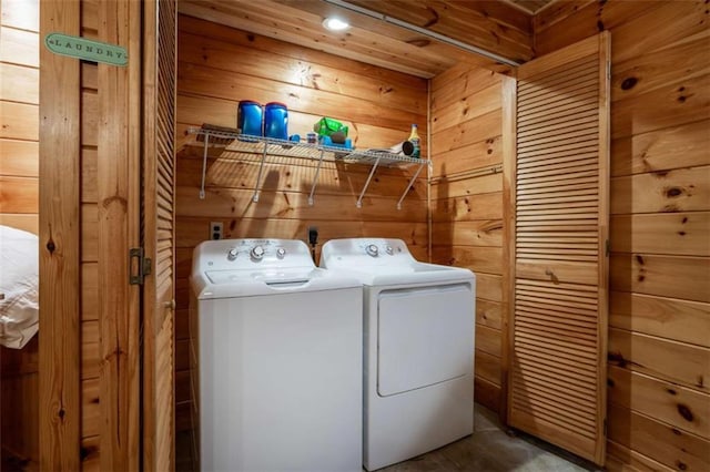 laundry room with washer and clothes dryer, laundry area, and wood walls