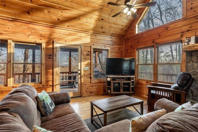 living area featuring ceiling fan, wooden walls, wood finished floors, and high vaulted ceiling