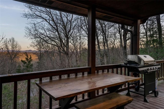 deck at dusk with outdoor dining area and area for grilling